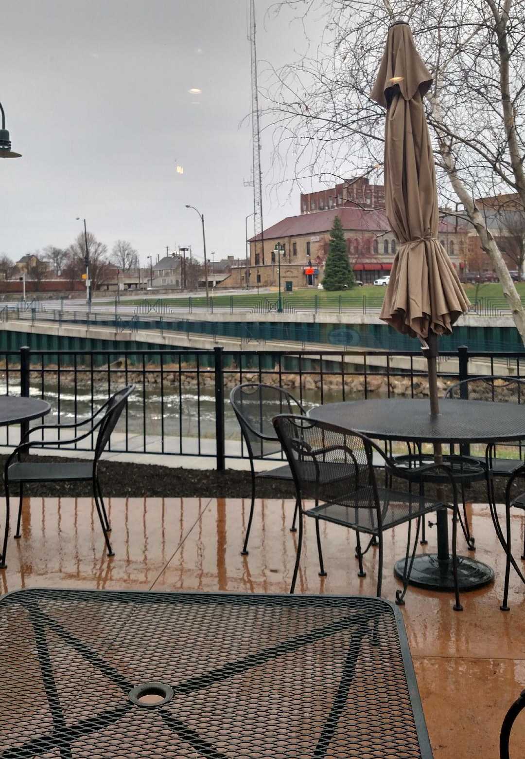 Hard amber and black duotone of an empty outdoor patio with metal chairs, riverside view, quiet mood