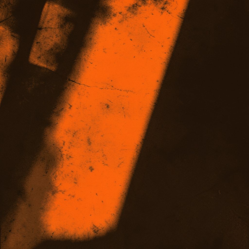 Hard two-tone duotone photograph in deep black and warm amber showing the interior of an industrial Indiana brewing room with copper and steel tanks, ladders and kegs, moody and shadowy