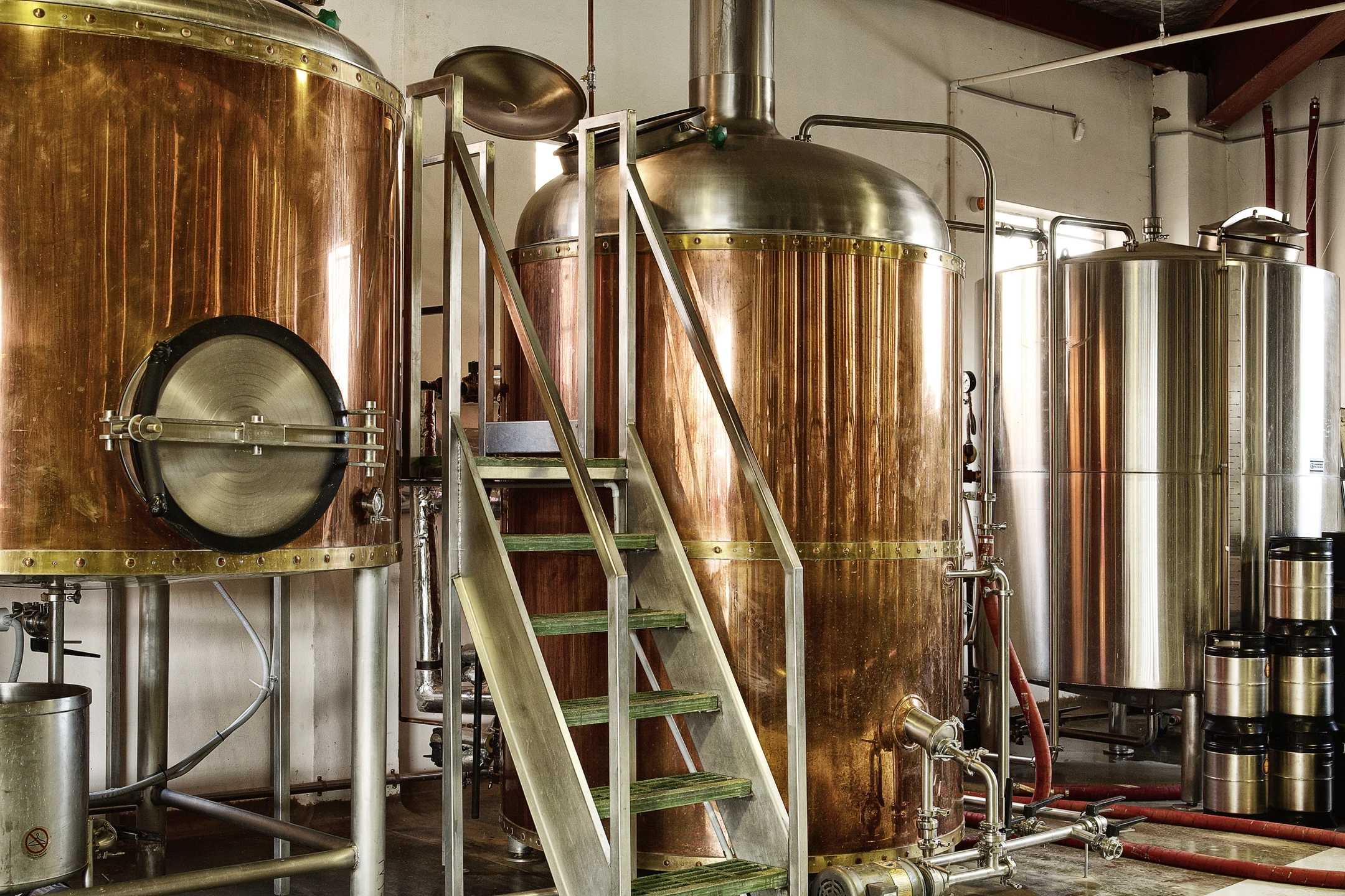 Hard amber and black duotone of copper and steel brewing tanks, warm metallic tones
